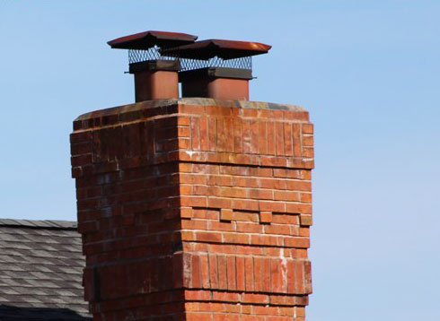 Chimney caps atop masonry chimney with blue sky - English Sweep Valley Park MO