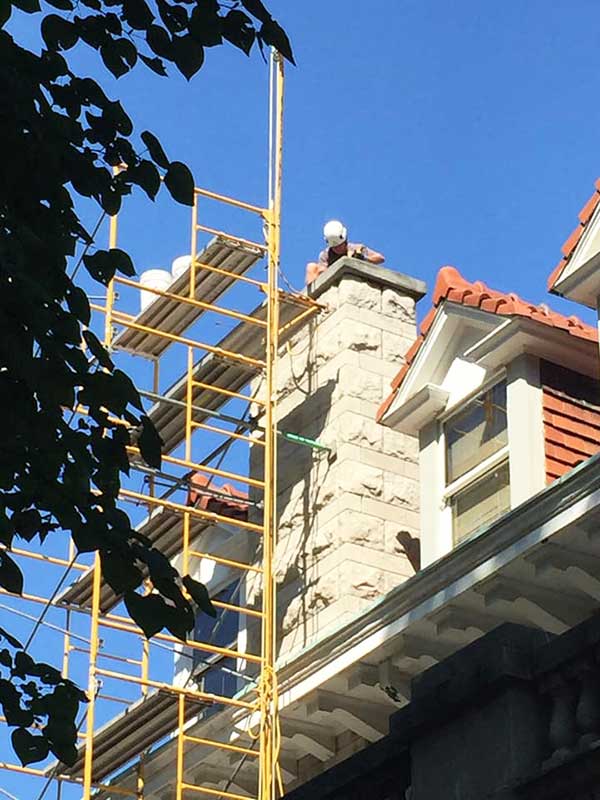 Constructing New Chimney with Scaffolding and tech sitting on crown of chimney