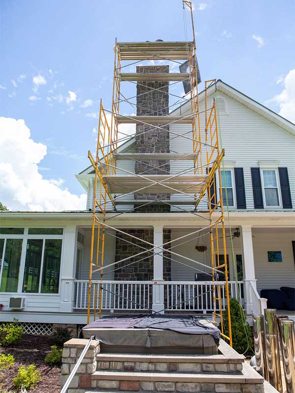 New Chimney Construction & Scaffolding in front of chimney white two story home