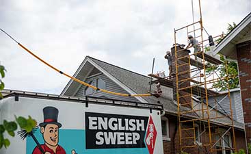 English Sweep truck in foreground with men on scaffolding working on chimney - English Sweep St. Louis MO