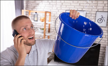 Man on the phone holding bucket leaky chimney 