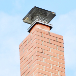 a light red masonry chimney with a metal chimney cap
