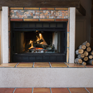 a wood-fueled fireplace insert with a pile of logs next to it