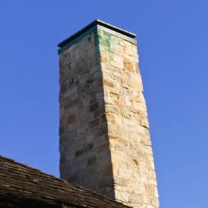 a light-colored masonry chimney with some staining
