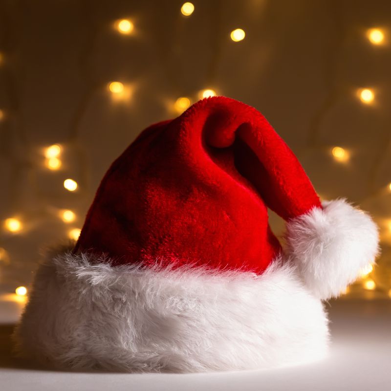 a red Santa hat with twinkle lights in the background
