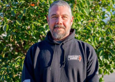 Joe M. - Production Coach has short graying hair, mustache and beard with a nice smile. He is black a black hooded English Sweep pull-over.
