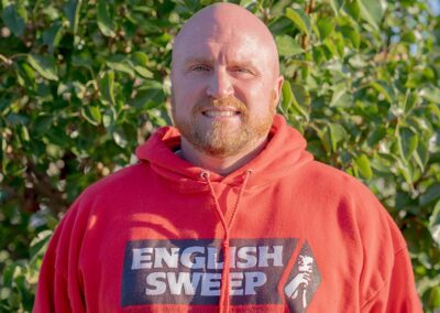 Matt O. - Sales & Service Tech has a shaved head with a red mustache and beard. He is wearing an English Sweep hooded pullover.
