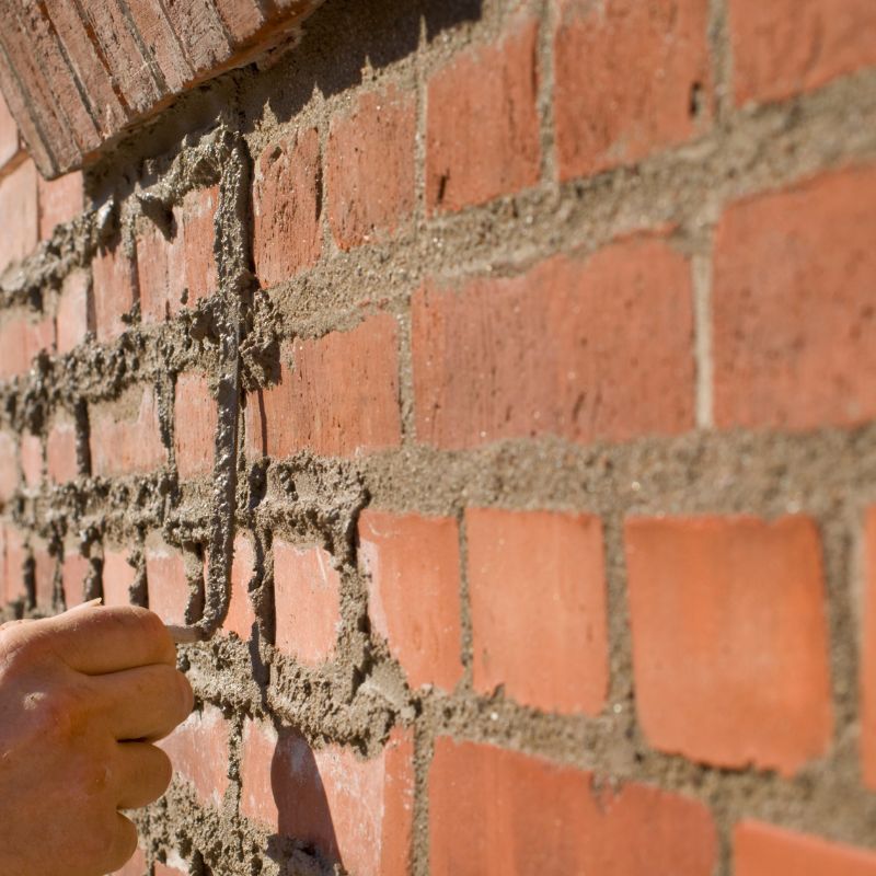 someone performing tuckpointing services on damaged masonry